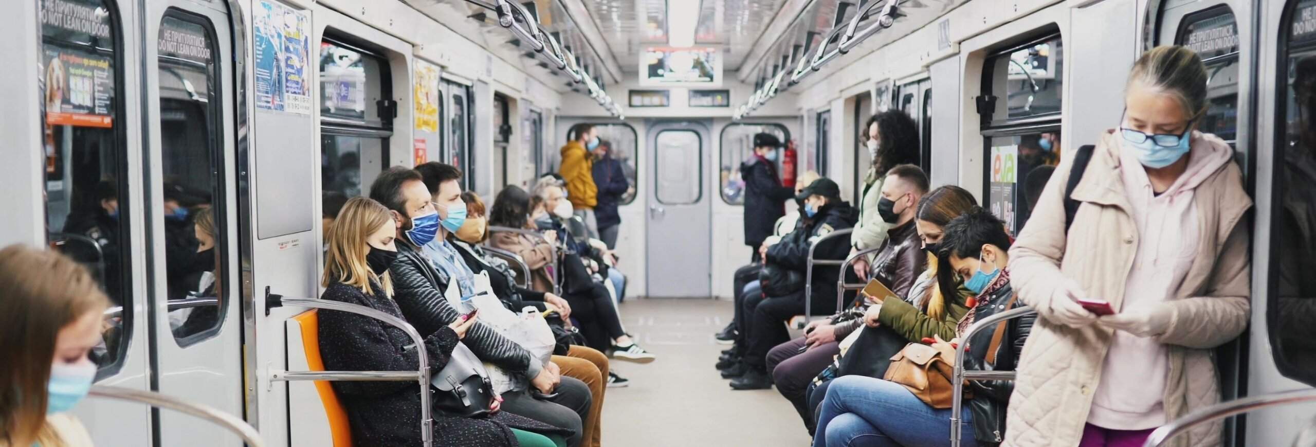 People sitting in a subway wearing masks
