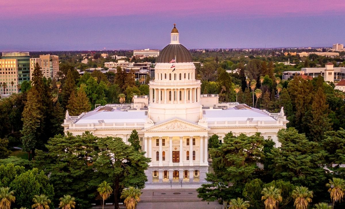 bird's eye view of the California State Capitol building at dusk, with a pink/purple sky in the background